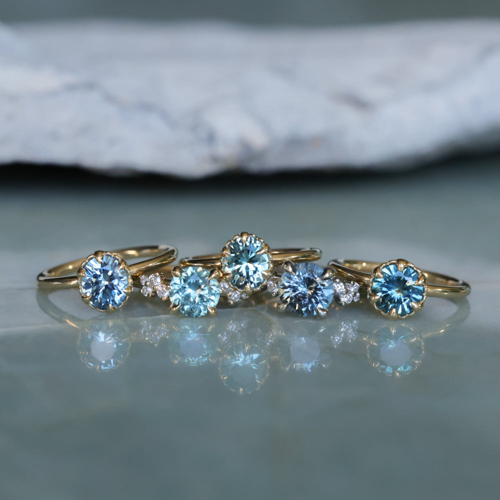 Set of gold rings with blue gemstones on a reflective surface