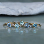 Set of gold rings with blue gemstones on a reflective surface