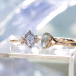 Two gold rings with gemstones on a reflective surface