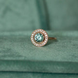 1.95ct Teal Montana Sapphire With Bezel Set Diamond Halo In 14k Rose Gold on table